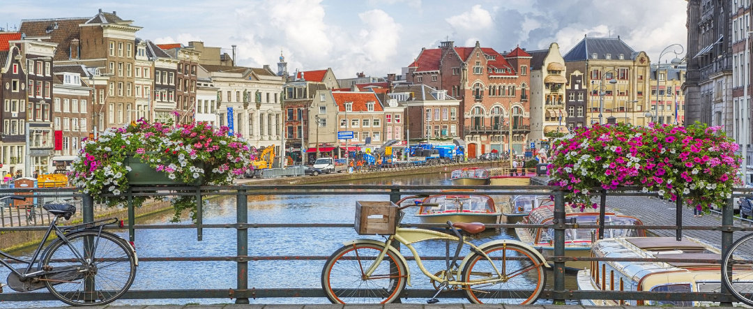 Vista de un puente de Amsterdam que atraviesa un canal y se aprecian los edificios.