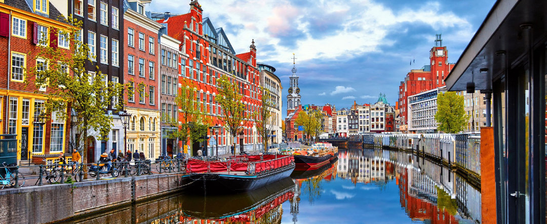 Vista de un canal en Amsterdam con reflejos de los edificios sobre el propio canal.
