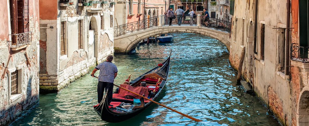 A Canal in Venice with a gondola and man rowing.