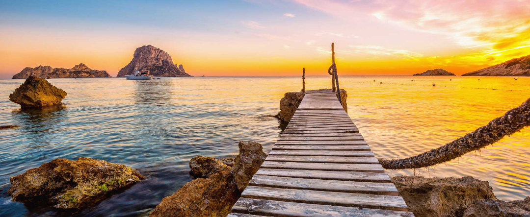 Cala de Ibiza, con pasarela de madera al atardecer.