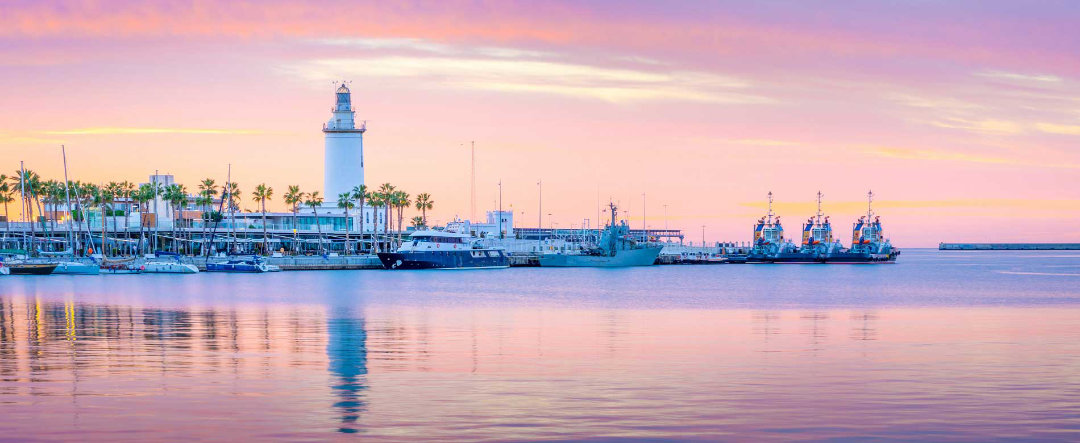 Marina and lighthouse in Málaga at sunset.