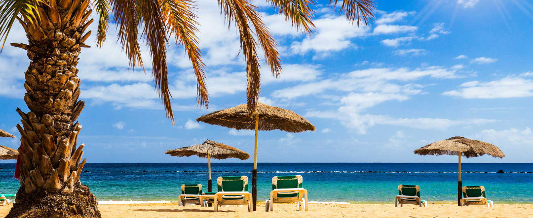 View of a beach in Tenerife, with sunbeds and shades.