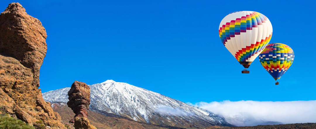 View of Mt. Teide with snow and hot-air balloons.
